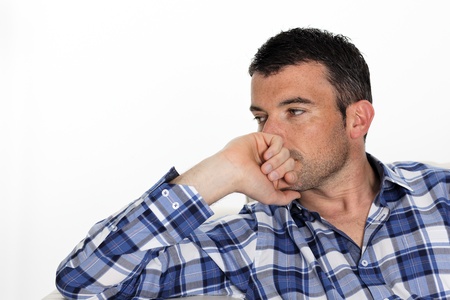 pensive man with blue shirt at homeの写真素材