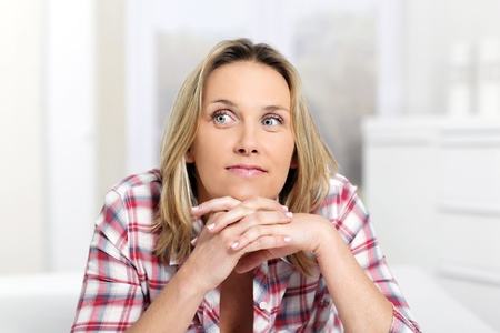 pensive blond woman at home on sofaの写真素材