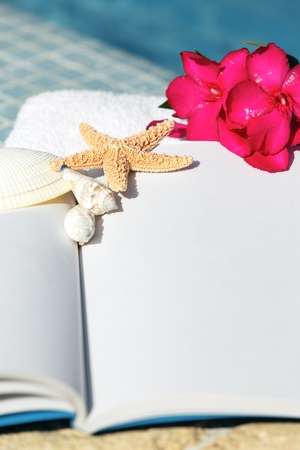 book, starfish, shellfish and white towel beside a pool の写真素材