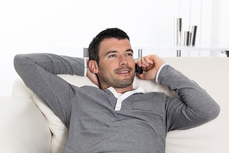 handsome man on the phone at home on sofaの写真素材