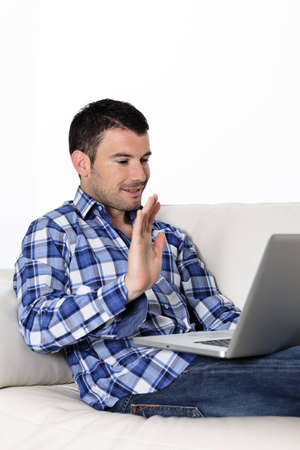 Portrait of a man waving at a laptopの写真素材