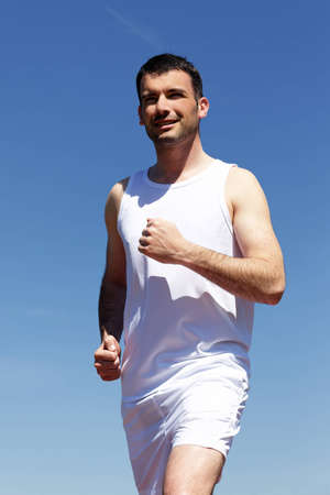 handsome man running outdoor with blue skyの写真素材