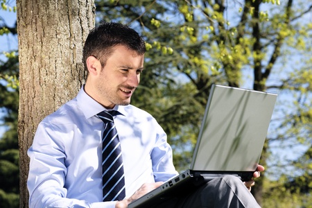handsome businessman working on laptop in a parkの写真素材