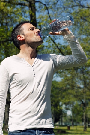 beautiful man drinking water in a parkの写真素材