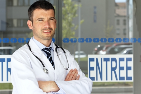 young handsome doctor in front of hospital entryの写真素材