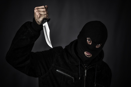 Thief in the hood on a black background の写真素材