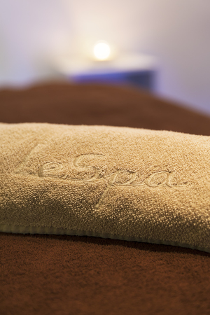 Wellness and spa concept with candles, towel and part of massage table.の写真素材