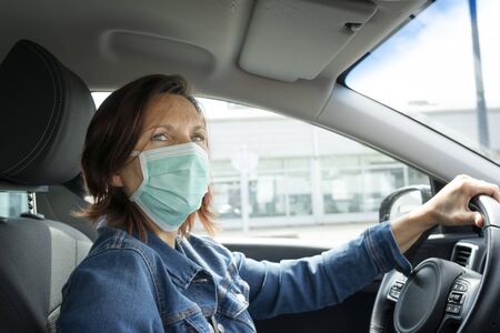 Woman driving her car with a mask on her faceの写真素材