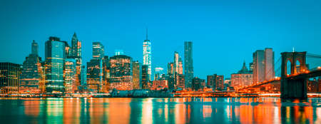 Panoramic view of New York City Manhattan midtown at dusk with skyscrapers illuminated over east riverの写真素材