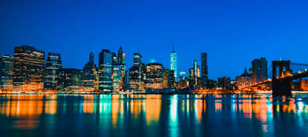 New York City Manhattan midtown at dusk with skyscrapers illuminated over east riverの写真素材