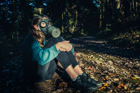Girl with gas mask in forest at sunsetの写真素材