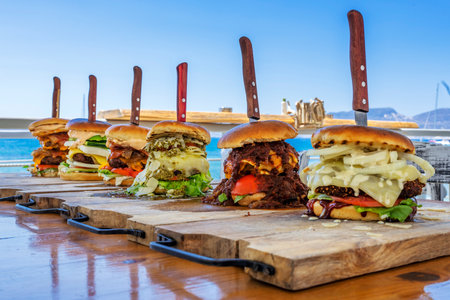 Six big burgers on a table in front of the seaの写真素材