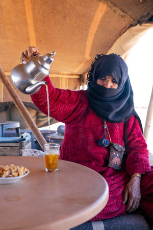 MERZOUGA, MOROCCO - JANUARY 3, 2024: Berber woman preparing tea for guests at a camp in the Merzouge desert, Morocco.のeditorial素材