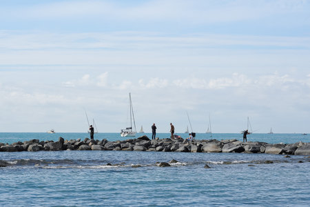 Italy, Rome - 16 October 2022: fishermen catch fish in the sea, stone breakwaterのeditorial素材
