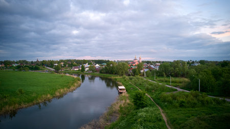 View of the Russian village on the bank of the river. A summer rural landscape. The Orthodox Church and houses among the trees. Summer city landscape in Suzdal Russiaの写真素材