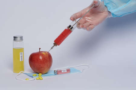 a doctor gives an injection of a vaccine into an appleの写真素材