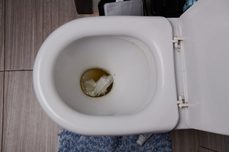 White dirty toilet with water and paper