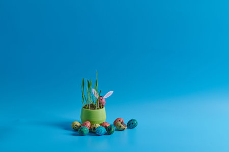 young grass and painted eggs on a blue background