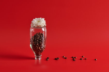 flowers in a bottle and grains of coffee on a red backgroundの写真素材