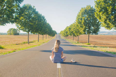 a young boy riding a skateboard up the side of a roadの写真素材
