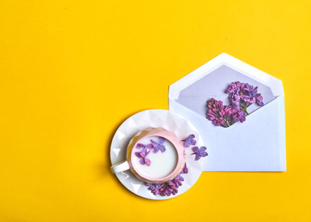 Lilac flowers in an envelope and a mug of coffee