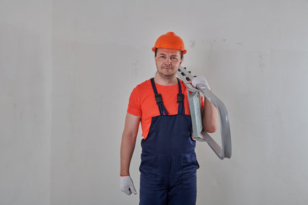 an electrician in a blue overalls holding a stepladder