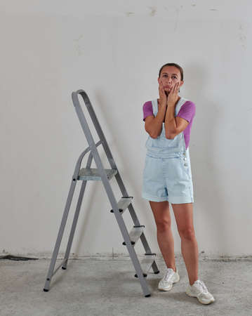 a sad repairman stands by the ladderの写真素材