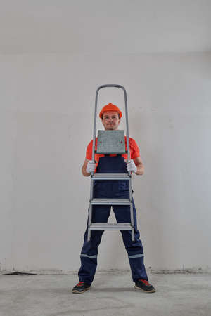 a man in a helmet is looking through a stepladderの写真素材
