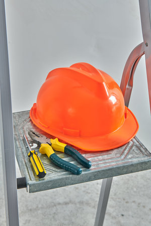 a screwdriver and an orange hard hat lies on the stairs