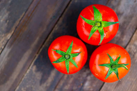 three small red tomatoes with a green leaf lieの写真素材