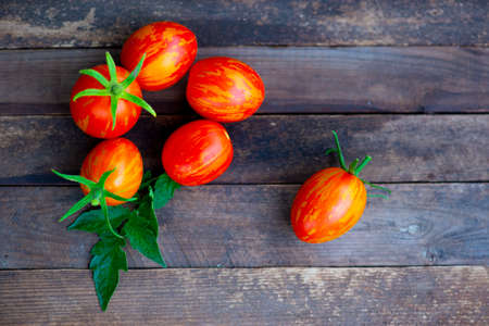 many small red tomatoes lie on a wooden backgroundの写真素材