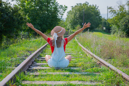 girl sitting with her back on the railroadの写真素材