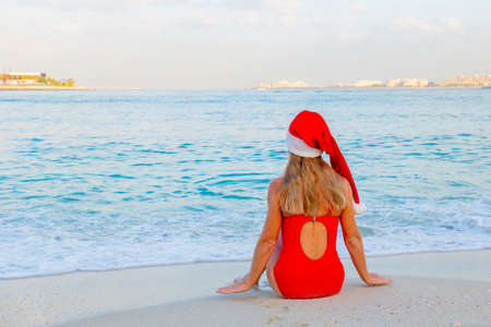 in a red swimsuit and a santa hat one girl on the beachの写真素材
