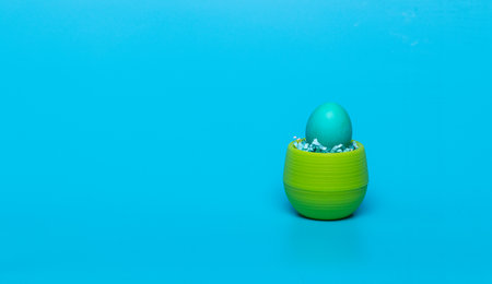 blue egg in a green jar on a blue backgroundの写真素材