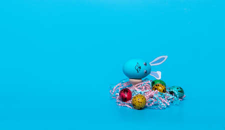 blue Easter egg with ears and colored quail eggsの写真素材