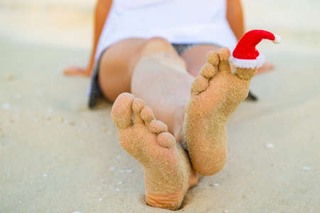 santa claus hat is worn on the toe on the beachの写真素材