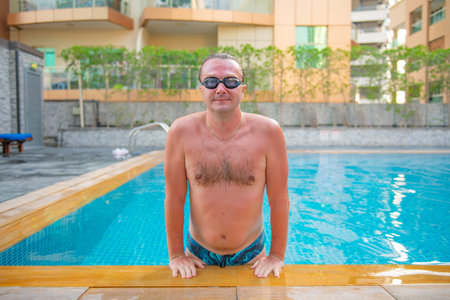 handsome guy with glasses swims in a large pool