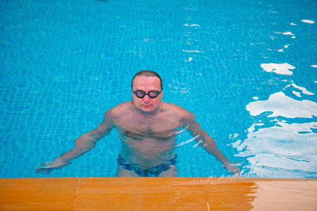 one inflated sportsman in glasses is training in the poolの写真素材