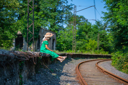a young woman in a green dress is sitting on the railwayの写真素材