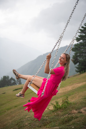 Dancing in the fresh sunlight a girl in a pink dress on a swing