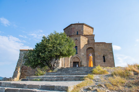 Serene Lady Wearing Orange Dress and White Scarf Standing by Historic Church