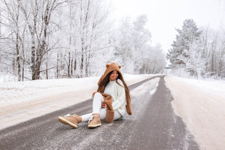 Young girl sitting on winter roadの写真素材