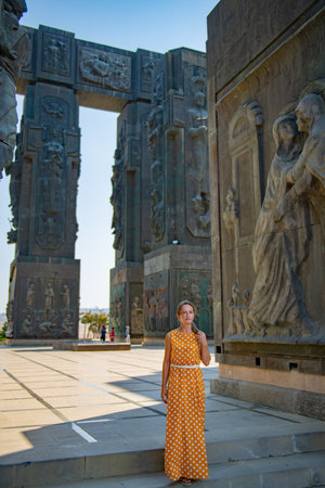 A girl in a yellow dress stands at the monument of the chronicles of Georgiaの写真素材