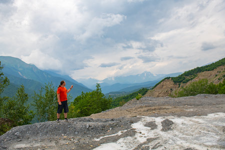 A man in red stands in the mountains of Georgiaの写真素材