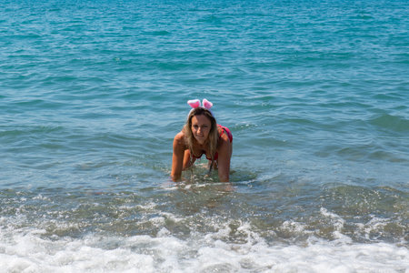 Santa Hat Splashes: Girl in Red Swimsuit Making Wavesの写真素材
