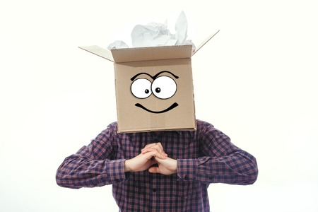 a man with a cardboard box on his head on a white background readingの写真素材