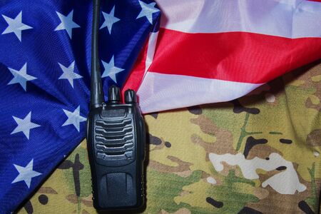 Portable black walkie-talkie on American flag and camouflage military backgroundの写真素材