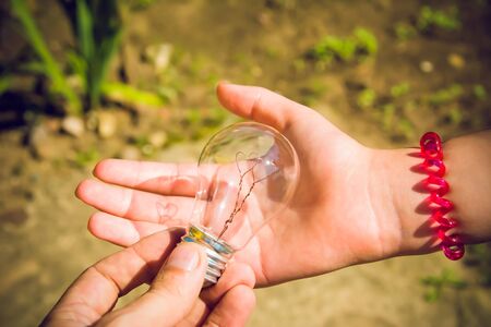 A young man passes a light bulb with hearts inside the girl. the concept of love in the family.の写真素材