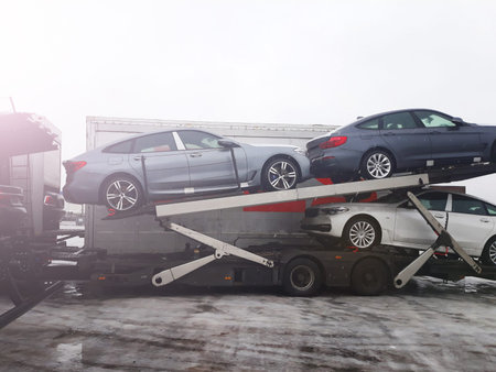 Loading new cars from conveyor of automobile plant on the truck for delivery to customers. Winter...