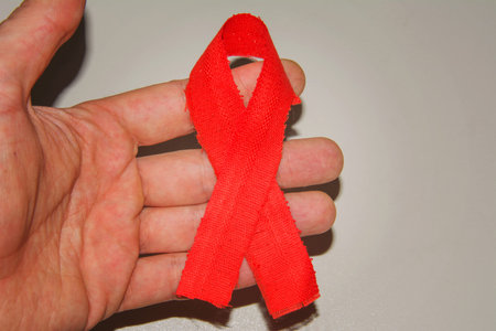 Man holding a red ribbon with ragged edges in his hand. Symbol of struggle and survival mankind. An...
